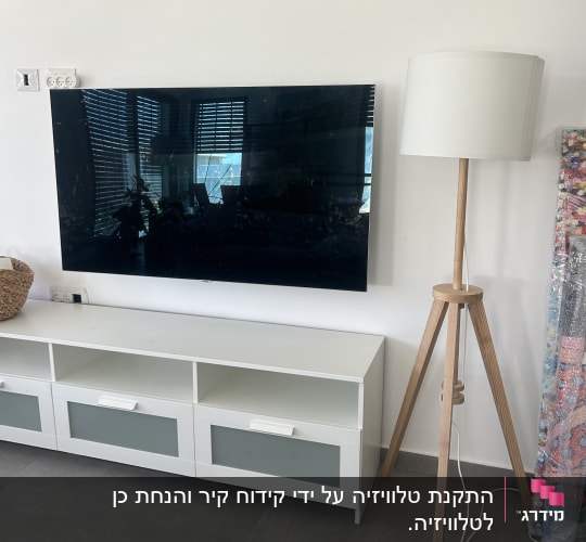 תליית טלוויזיה על קיר גבס/בטון בסלון מעל מזנון לבן